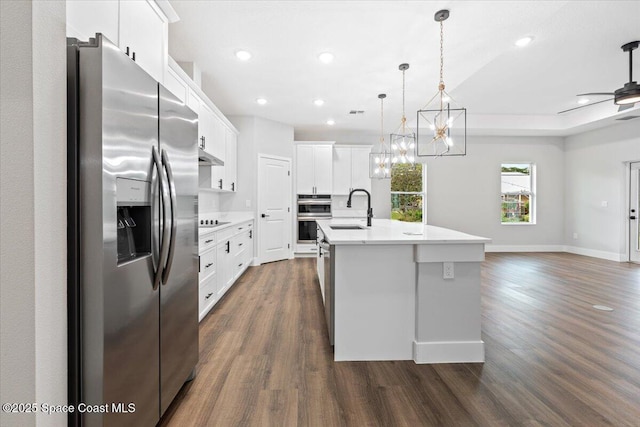 kitchen featuring hanging light fixtures, appliances with stainless steel finishes, sink, white cabinetry, and a kitchen island with sink