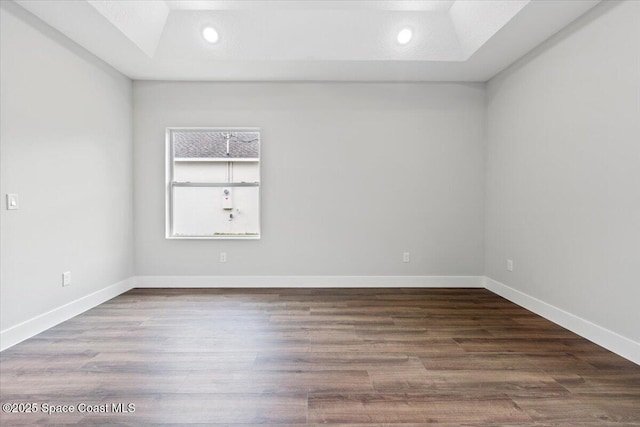 empty room with hardwood / wood-style floors and a tray ceiling