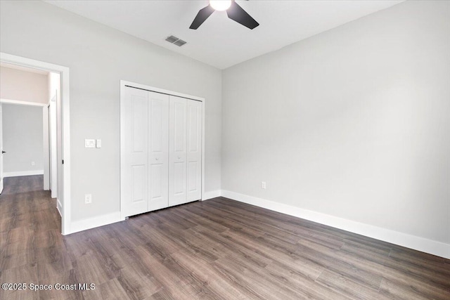 unfurnished bedroom with dark wood-type flooring, a closet, and ceiling fan