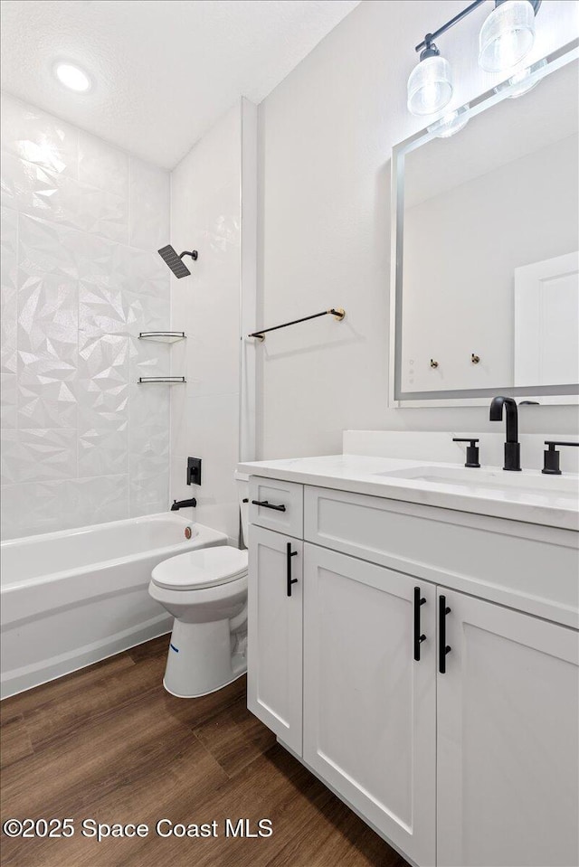 full bathroom with vanity, toilet, tiled shower / bath combo, and wood-type flooring