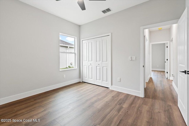 unfurnished bedroom with ceiling fan, wood-type flooring, and a closet