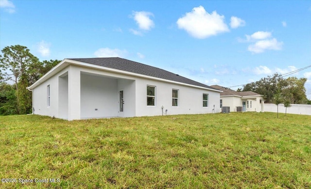 rear view of property with central air condition unit and a lawn