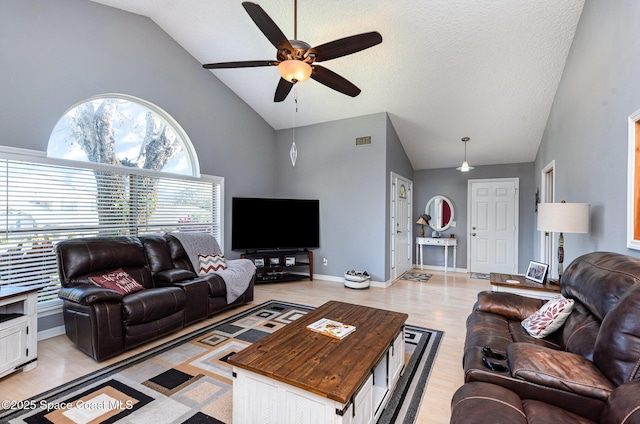 living room with ceiling fan, high vaulted ceiling, a textured ceiling, and light wood-type flooring