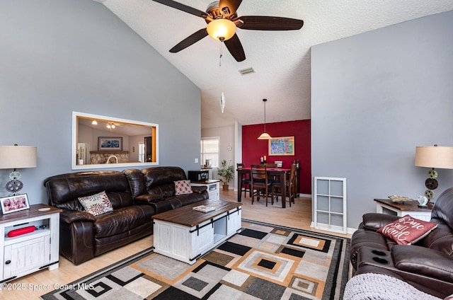 living room with high vaulted ceiling, ceiling fan, and light wood-type flooring