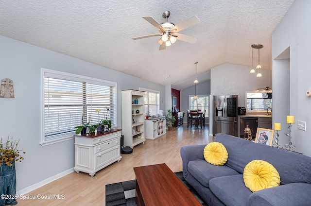 living room with lofted ceiling, light wood-type flooring, a textured ceiling, and a wealth of natural light