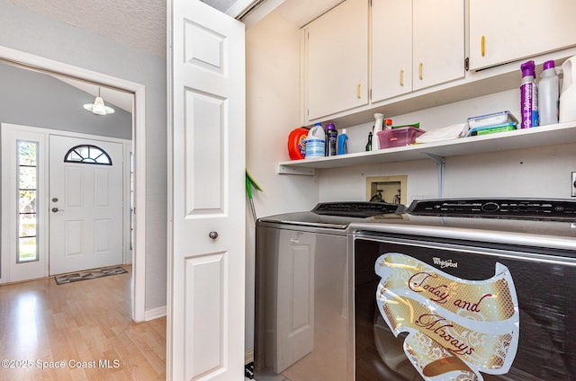 laundry room with light hardwood / wood-style flooring, cabinets, and washing machine and clothes dryer