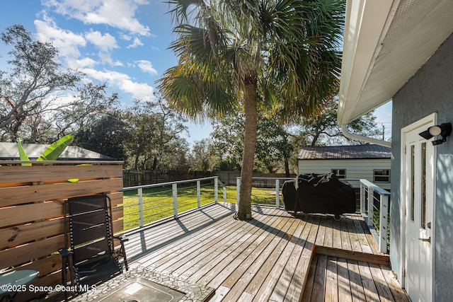 wooden terrace featuring grilling area and a yard