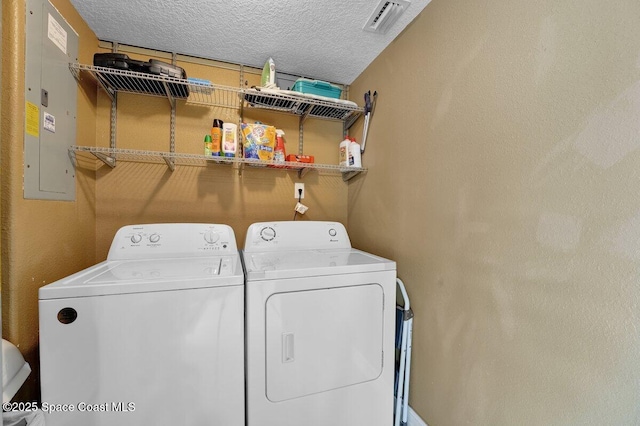 laundry area featuring washing machine and dryer, electric panel, and a textured ceiling