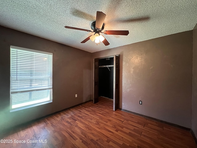 unfurnished bedroom featuring a closet, ceiling fan, dark wood-type flooring, and a textured ceiling