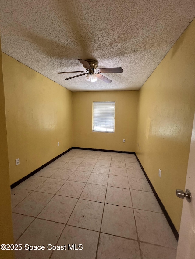 spare room featuring ceiling fan, a textured ceiling, and light tile patterned flooring