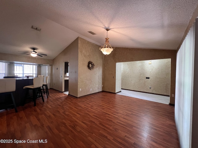 living room with hardwood / wood-style flooring, a textured ceiling, ceiling fan, and vaulted ceiling