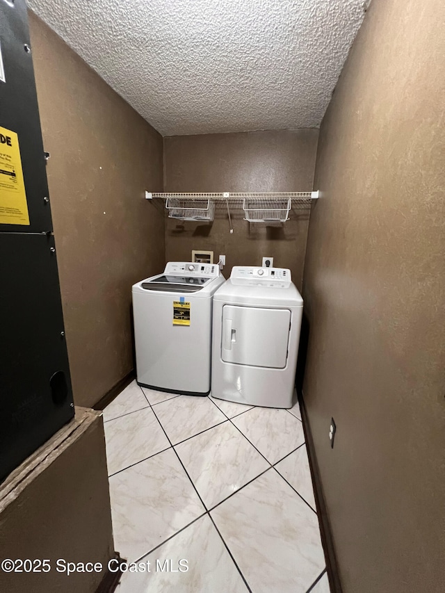 laundry room featuring washer and dryer, a textured ceiling, and light tile patterned floors