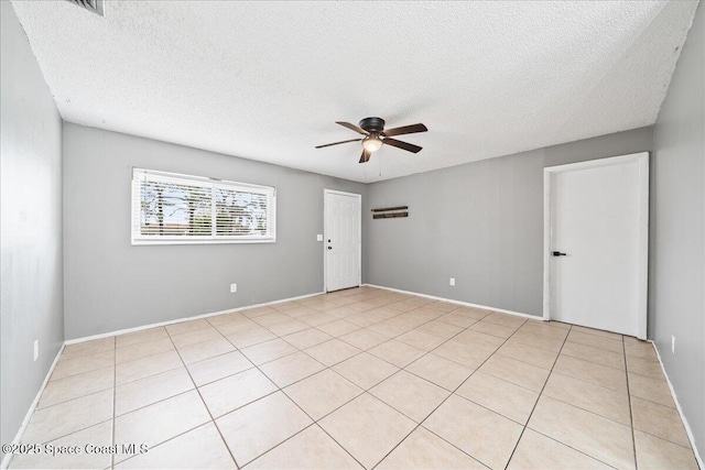 empty room featuring light tile patterned floors, a ceiling fan, and a textured ceiling