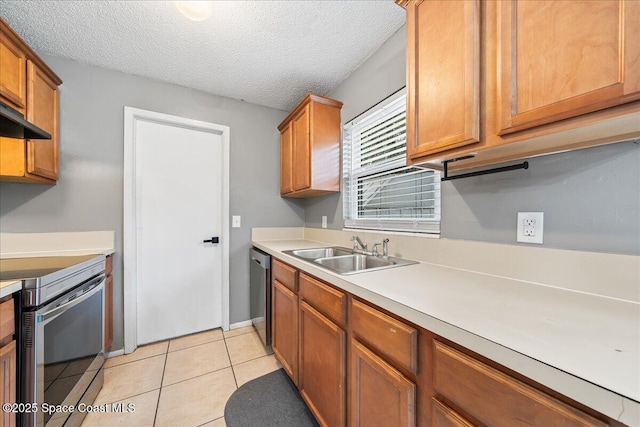 kitchen featuring light tile patterned floors, stainless steel appliances, a sink, light countertops, and brown cabinets