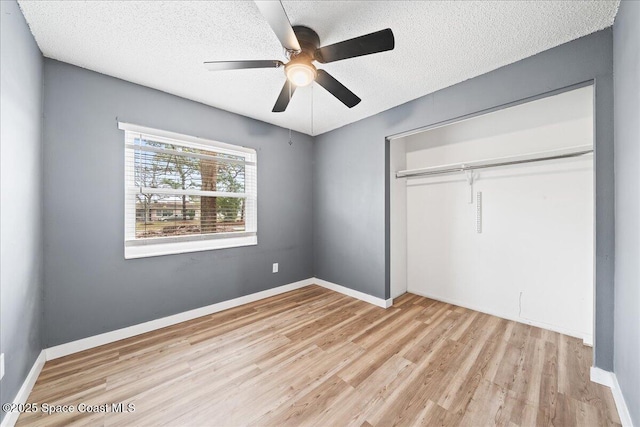 unfurnished bedroom with a textured ceiling, a closet, ceiling fan, and light wood-type flooring