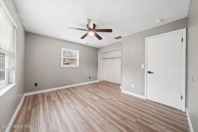 unfurnished bedroom featuring visible vents, light wood-type flooring, a closet, and a textured ceiling