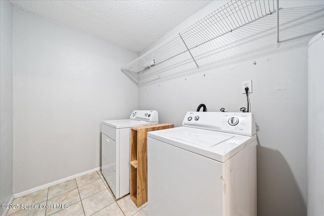 laundry area featuring baseboards, laundry area, light tile patterned flooring, a textured ceiling, and washer and dryer