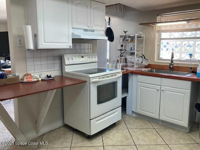 kitchen with white cabinetry, sink, light tile patterned flooring, and white electric range oven