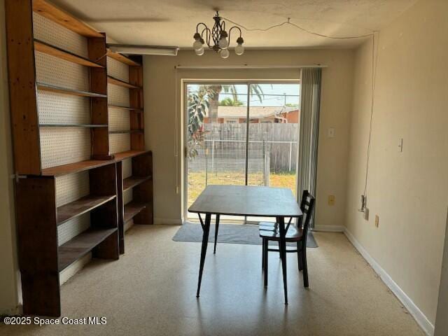 dining space with a chandelier, baseboards, and light colored carpet