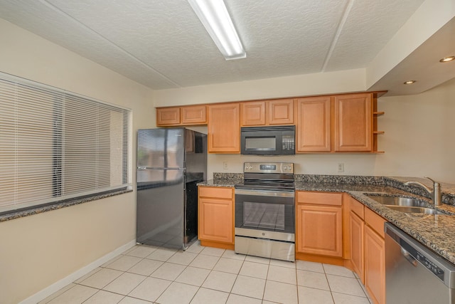 kitchen with a textured ceiling, black appliances, dark stone counters, sink, and light tile patterned floors