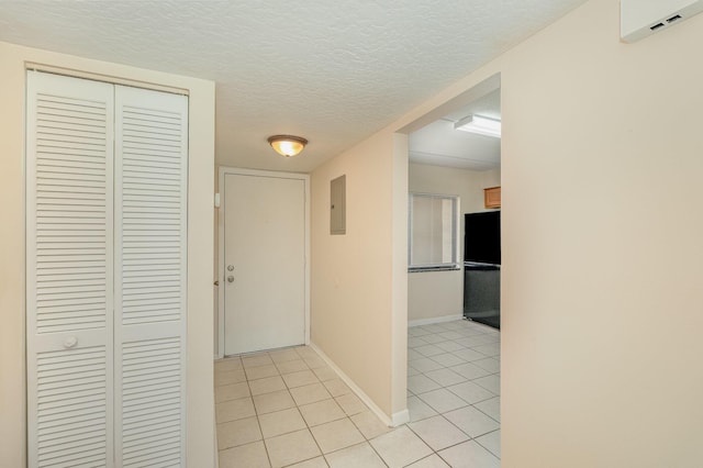 hall with a textured ceiling, light tile patterned floors, and electric panel