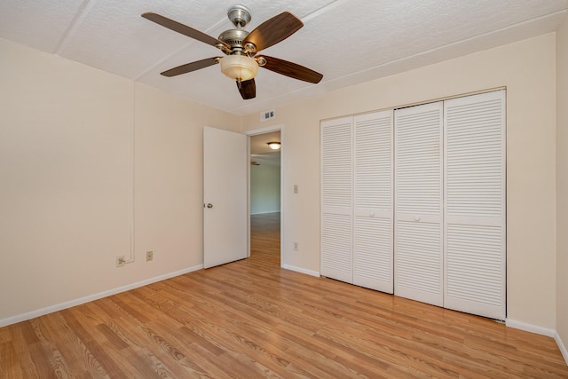 unfurnished bedroom with light wood-type flooring, ceiling fan, a textured ceiling, and a closet