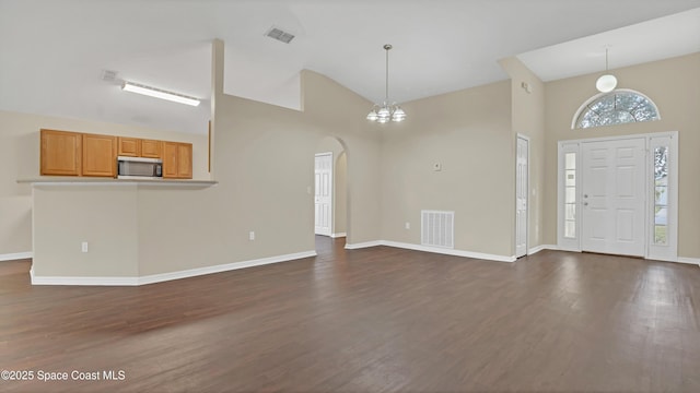 foyer featuring dark wood-type flooring, a towering ceiling, and a notable chandelier