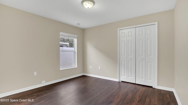 unfurnished bedroom featuring a closet and dark wood-type flooring