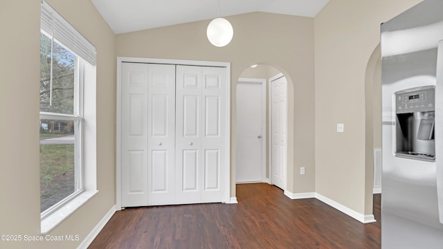 unfurnished bedroom with a closet, multiple windows, dark hardwood / wood-style floors, and lofted ceiling