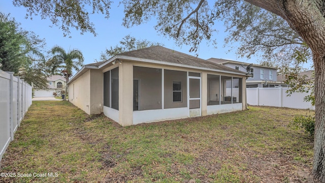 rear view of property featuring a lawn and a sunroom