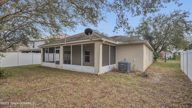 rear view of property with central AC unit, a yard, and a sunroom