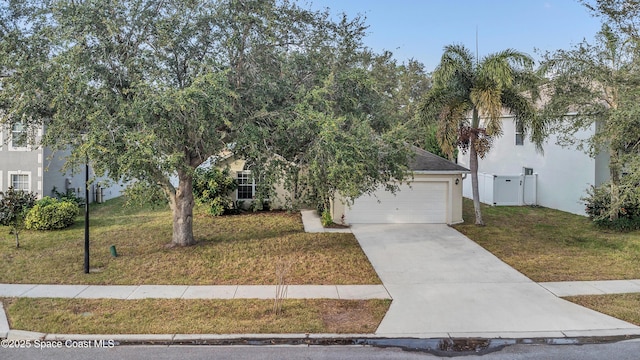 view of property hidden behind natural elements featuring a garage and a front lawn