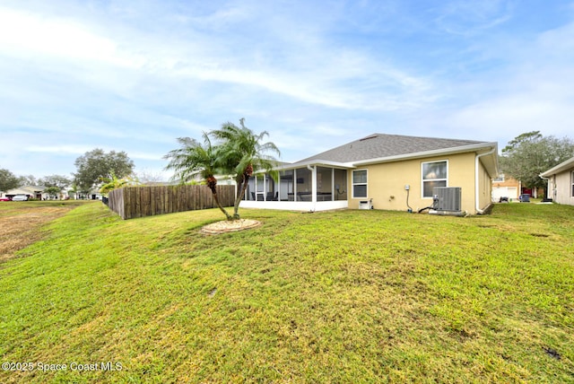 rear view of property featuring a sunroom, a yard, and cooling unit