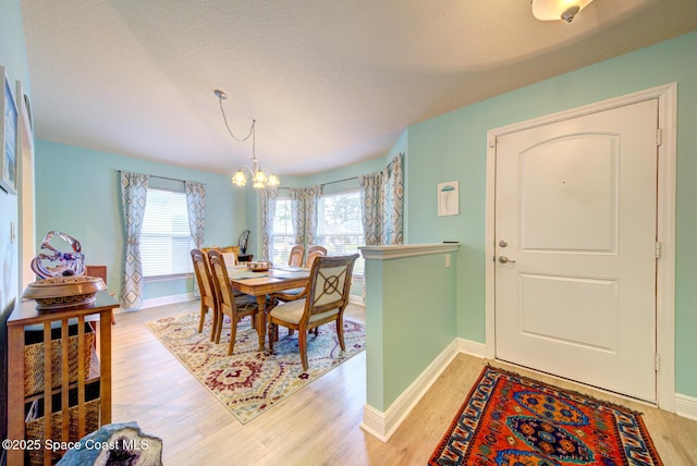 dining space with an inviting chandelier, light hardwood / wood-style floors, and a textured ceiling