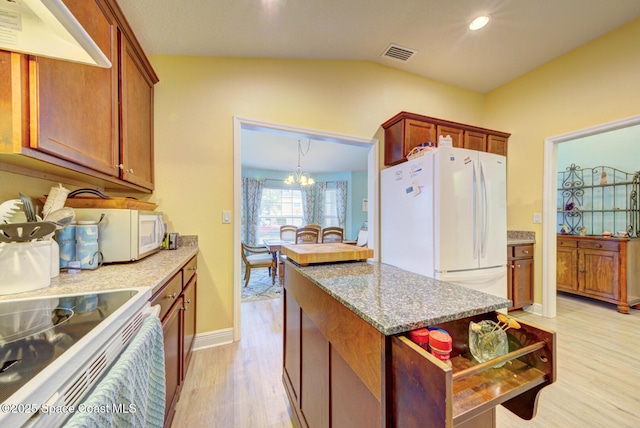 kitchen featuring light stone counters, white appliances, a notable chandelier, light hardwood / wood-style floors, and lofted ceiling