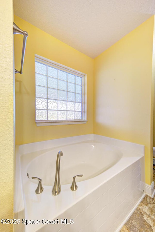 bathroom featuring a tub and a textured ceiling