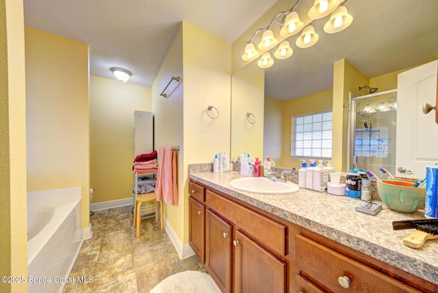 bathroom with a textured ceiling, vanity, and shower with separate bathtub