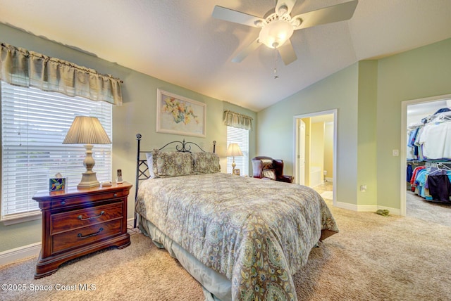 carpeted bedroom featuring vaulted ceiling, ensuite bathroom, ceiling fan, a walk in closet, and a closet