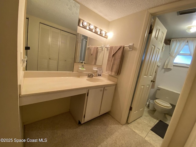 bathroom with vanity, toilet, and a textured ceiling