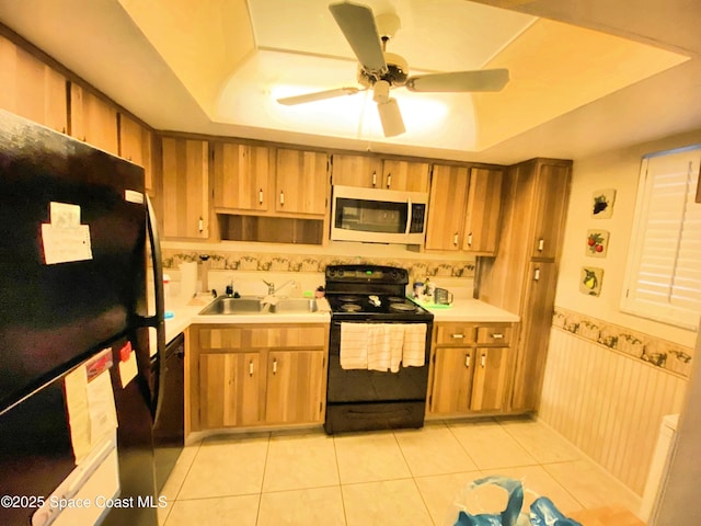 kitchen with light tile patterned flooring, a raised ceiling, sink, and black appliances