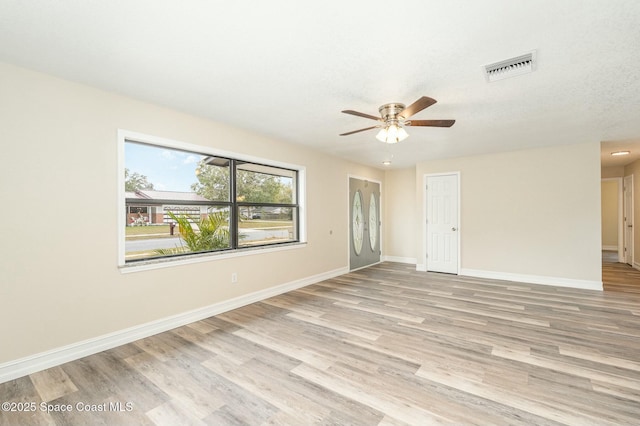 empty room with ceiling fan and light hardwood / wood-style flooring