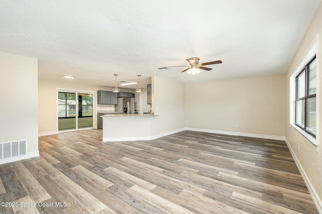 unfurnished living room featuring ceiling fan, a textured ceiling, and dark hardwood / wood-style flooring