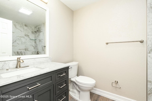 bathroom with wood-type flooring, tiled shower, toilet, and vanity