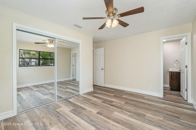 unfurnished bedroom with a closet, ceiling fan, light hardwood / wood-style flooring, and a textured ceiling