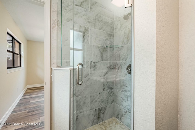 bathroom with a shower with shower door and hardwood / wood-style flooring