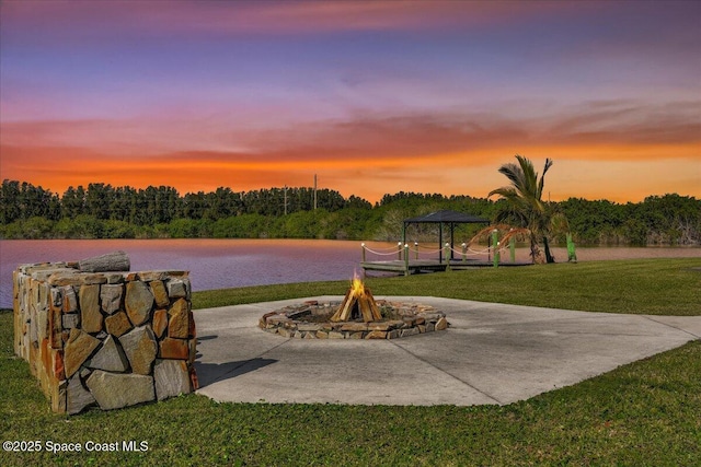 exterior space with a gazebo, a water view, a fire pit, and a lawn