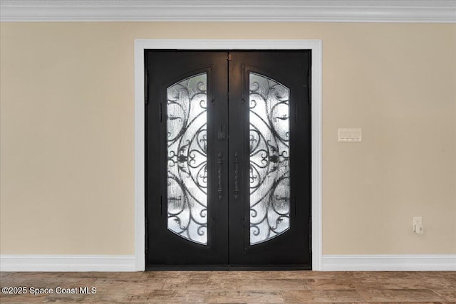 entrance foyer with crown molding and french doors