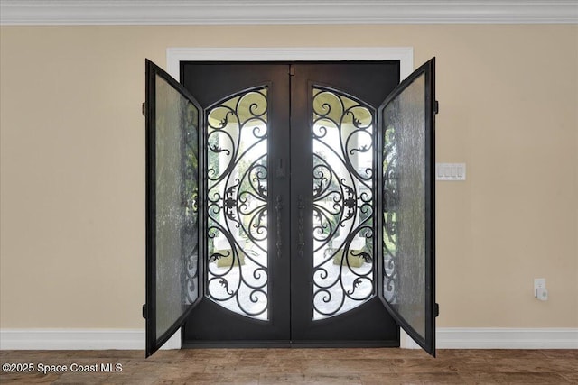 foyer entrance with crown molding, wood-type flooring, and french doors