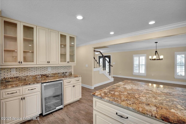 kitchen featuring crown molding, light hardwood / wood-style flooring, light stone countertops, a textured ceiling, and beverage cooler