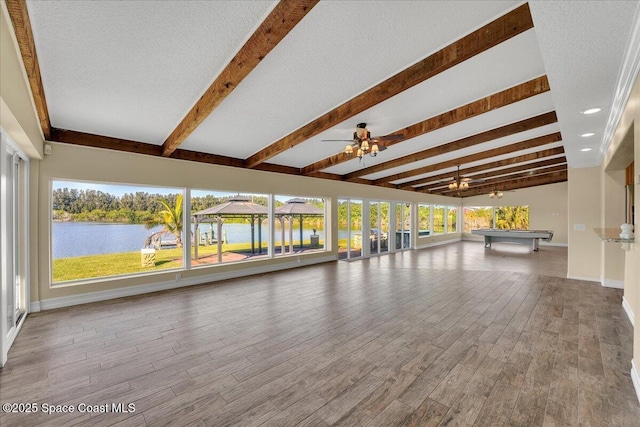 interior space with ceiling fan, a water view, and beam ceiling